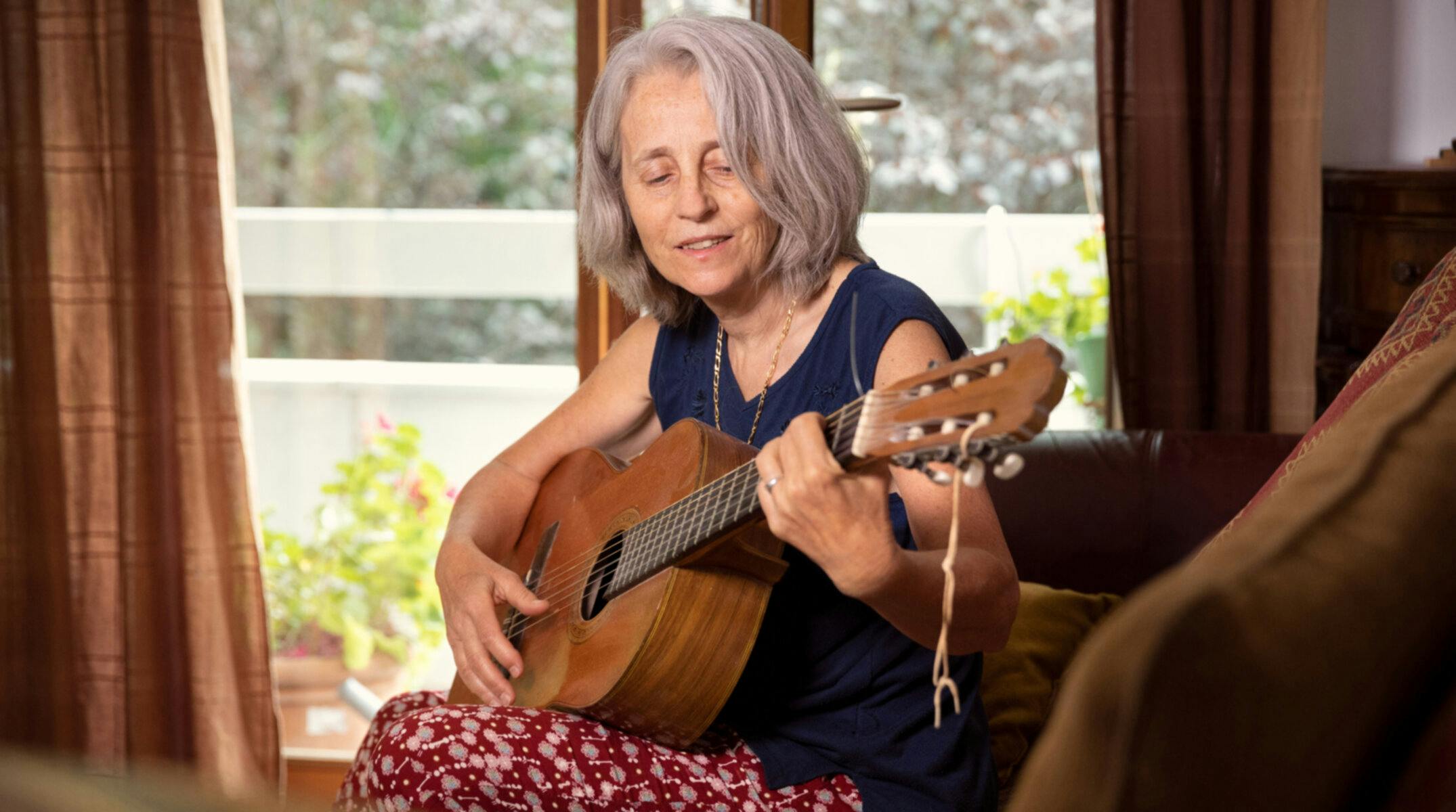Femme d'une soixantaine d'années qui joue de la guitare